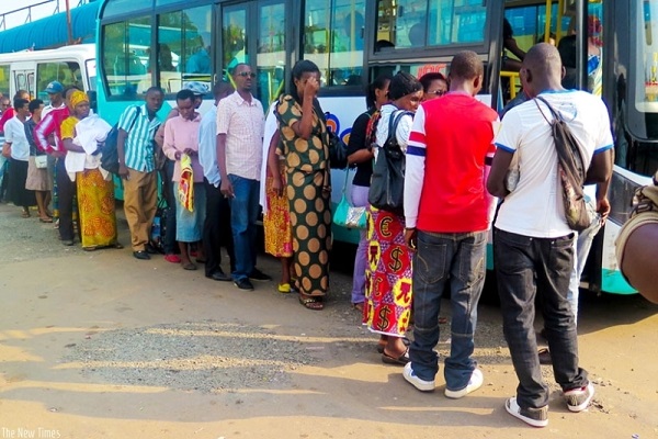Rwandans queue up next to a bus