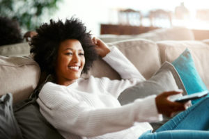 Shot of a young woman relaxing on the sofa at home and watching tv