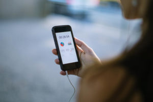 Close up of woman holding smart phone and using fitness app to check her training progress.