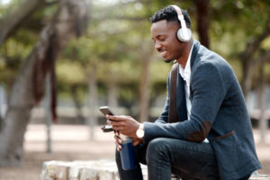 Shot of a young businessman using a smartphone and headphones in the city